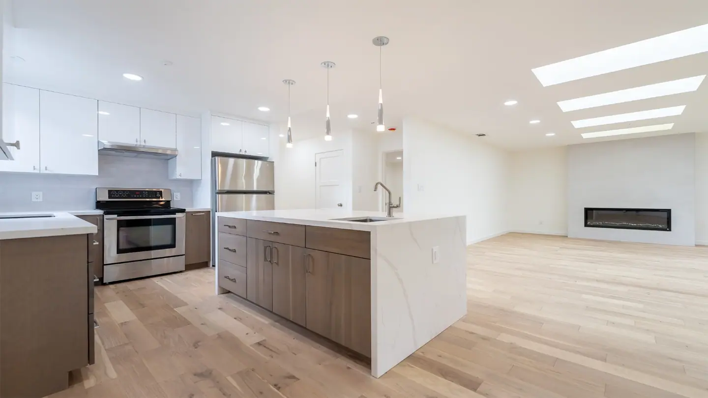 Open-concept kitchen and living room with a waterfall island and skylights after a Menlo Park whole-home renovation