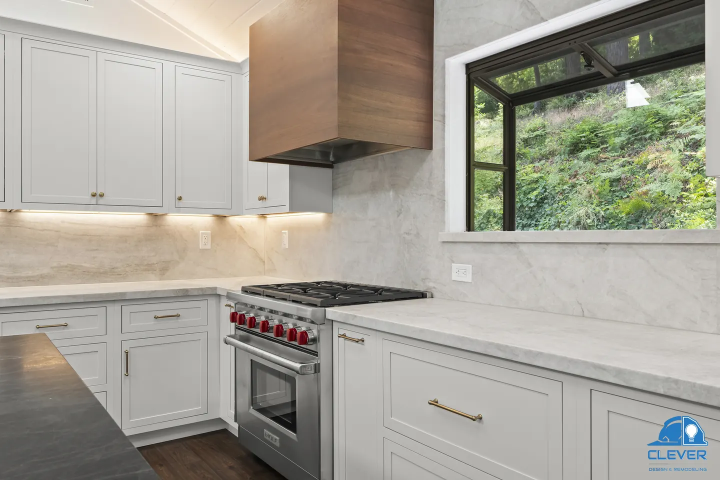 White shaker cabinets with brass pulls and a picture window over the wooded hillside, kitchen and bath remodel in Los Gatos, CA