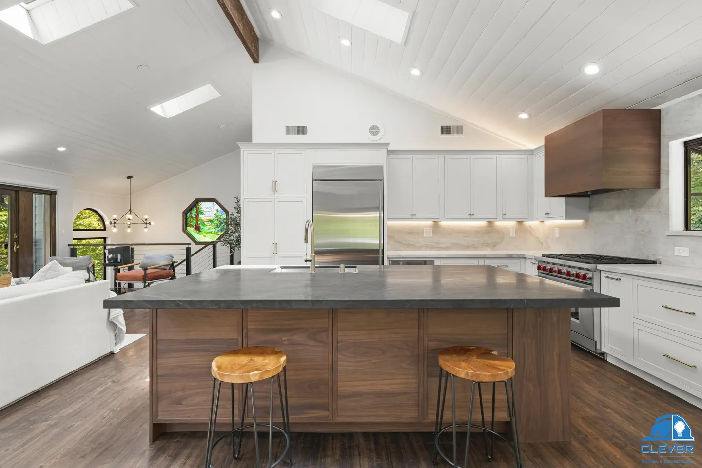 Walnut island with a dark stone top and wood stools, with a built-in refrigerator and pro-style range beyond, kitchen and bath remodel in Redwood City, CA