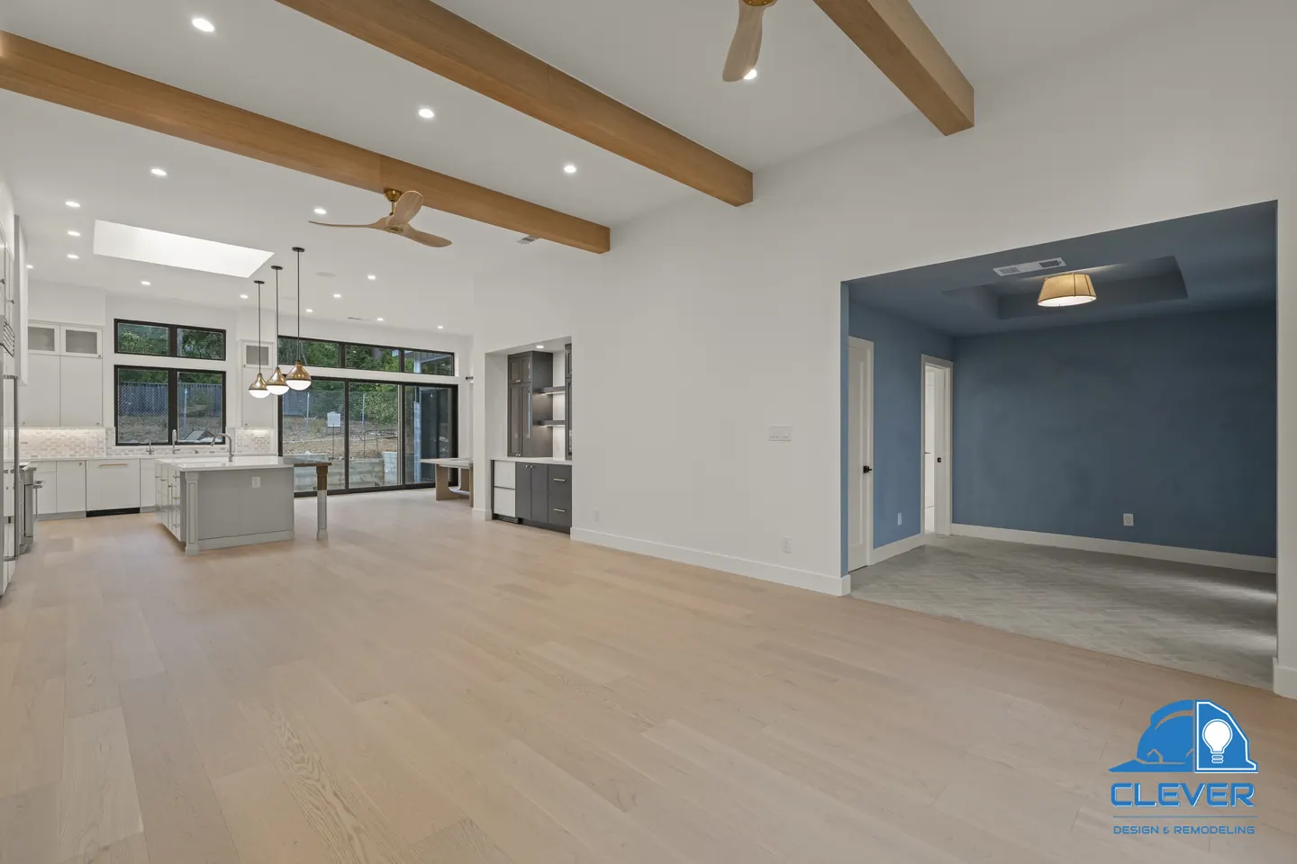 Beamed living room with white oak floors, opening to the kitchen and a blue-walled entry, whole-home remodel in Palo Alto, CA