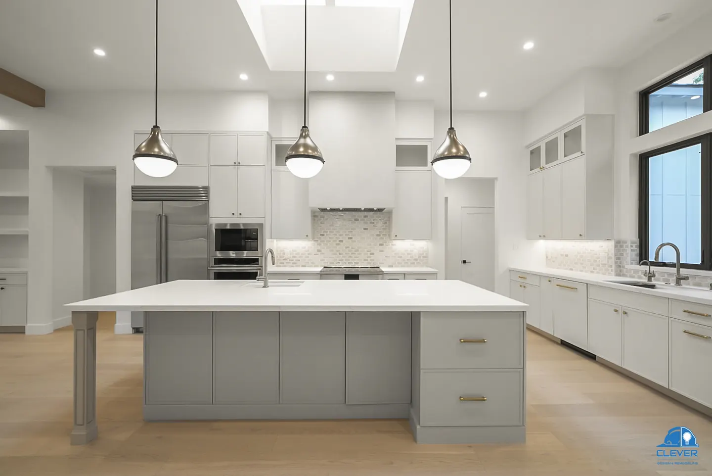 Long gray kitchen island with white quartz and three pendant lights under a skylight, whole-home remodel in Saratoga, CA