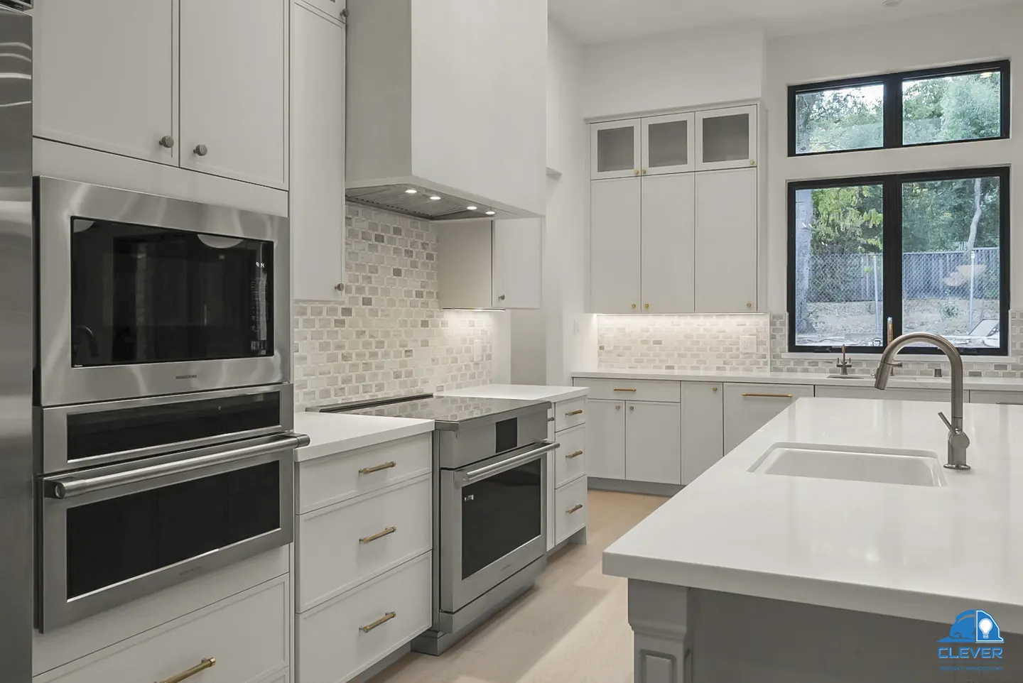 Double wall ovens, a stainless range and a mosaic tile backsplash beside a black-framed window, whole-home remodel in Saratoga, CA