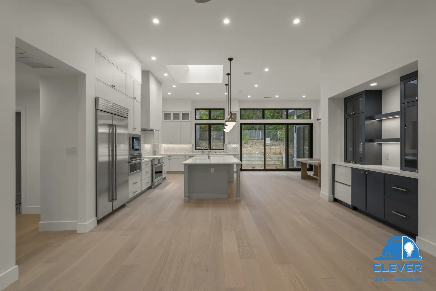 View through to the kitchen past a navy built-in bar, with black-framed sliding doors at the back, whole-home remodel in Saratoga, CA
