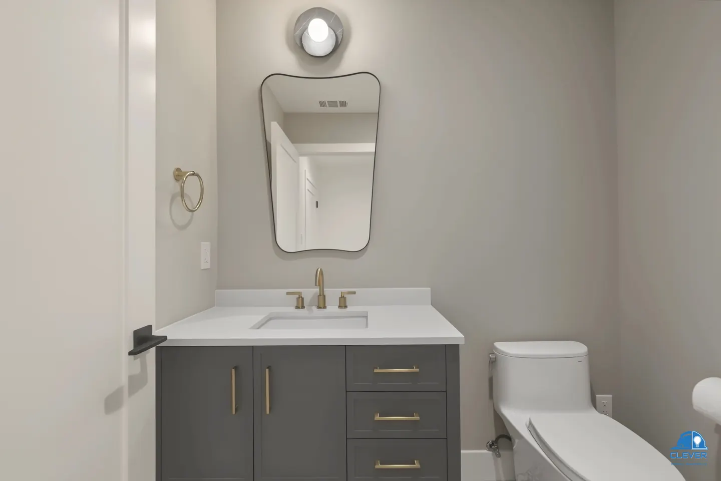 Powder room with a gray vanity, brass hardware and a curved black-framed mirror, whole-home remodel in Saratoga, CA